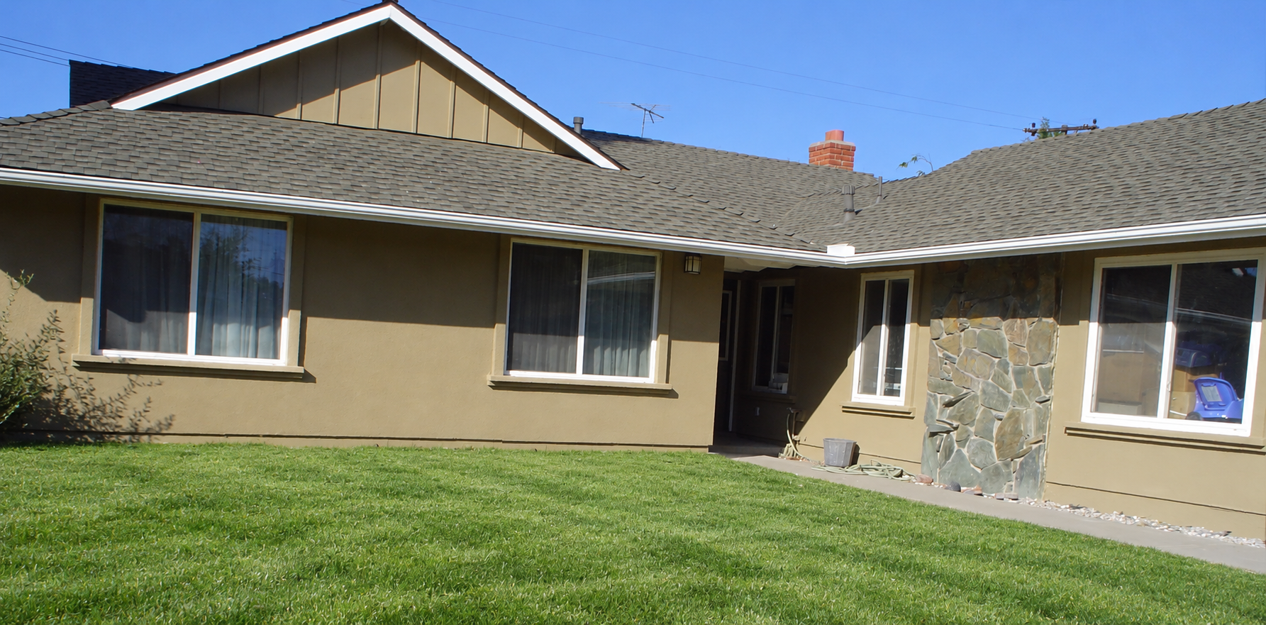 Home with replacement windows and a green lawn; landscaping digitally retouched.